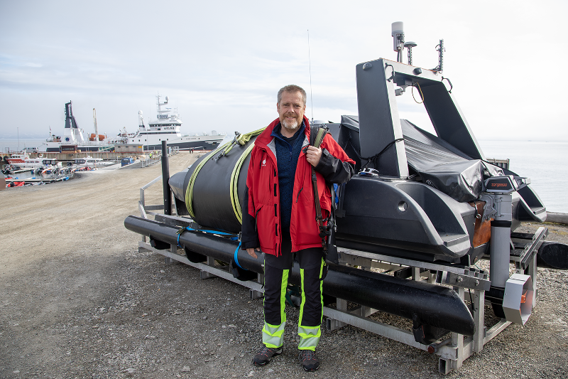 Jørgen Berge i Ny-Ålesund, foran det selvgående fartøyet som skal brukes i forskningen framover. 